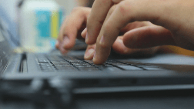 Hands typing on a keyboard in an office