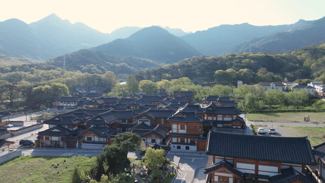 Hanok village with grassy field beneath mountain