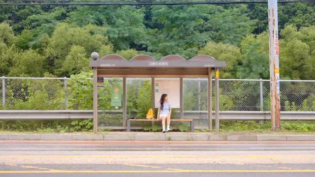 시골의 버스 정류장에서 기다리는 여성