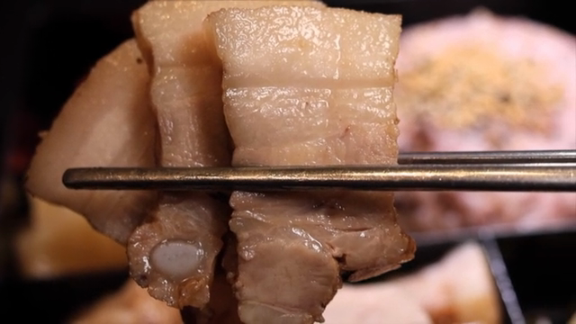 Chopsticks holding slices of bossam