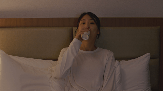 Woman sitting on bed drinking a can coffee