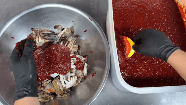 Spicy sauce being poured over marinated crab