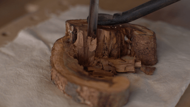 Woodcraft artisan carving wood piece with chisel on table