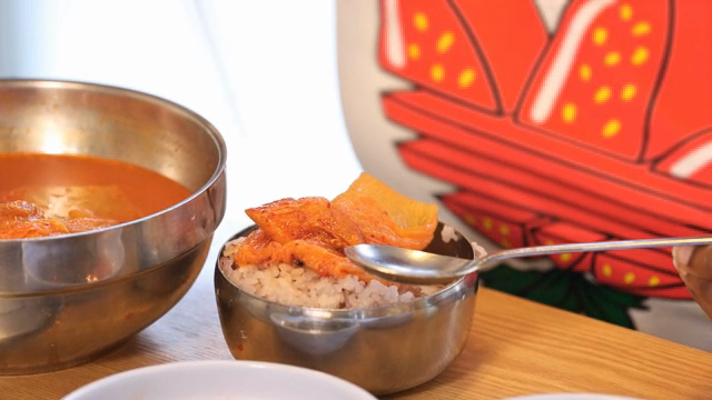 Kimchi being placed on rice in a bowl