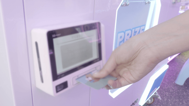 Person using a card at a gacha vending machine in a shop