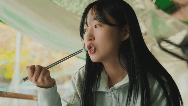 Young woman eating white chicken soup with chopsticks in mountain lodge