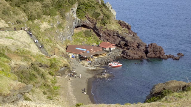 Coastal cliff with a small harbor and boats