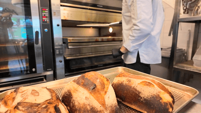 갓 구운 빵을 오븐에서 꺼내는 제빵사