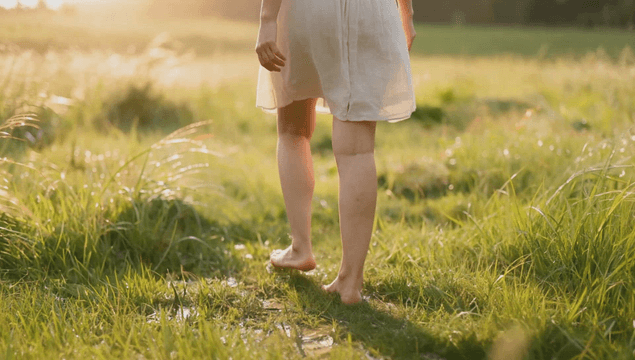 Woman walking barefoot in a sunlit meadow