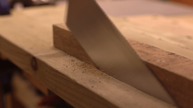 Wood being cut with a saw on a workbench