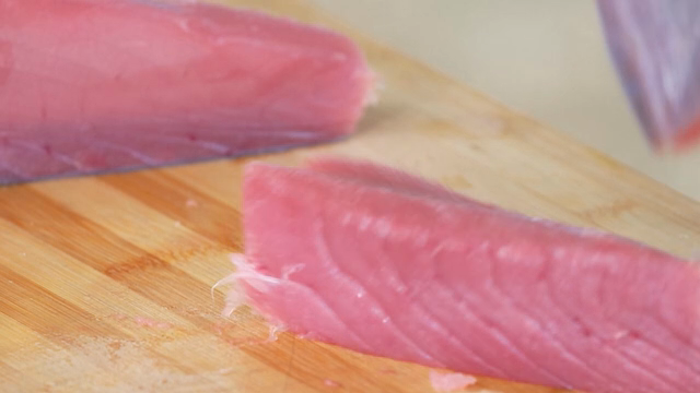 Slicing fresh tuna on a wooden board