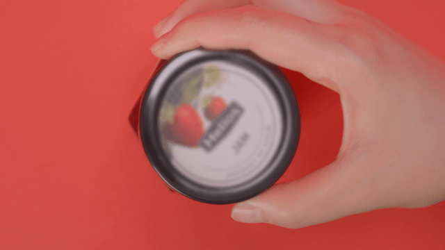 Jar of strawberry jam on a red background