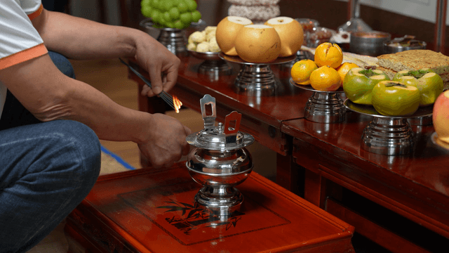 Person lighting incense at ancestral table