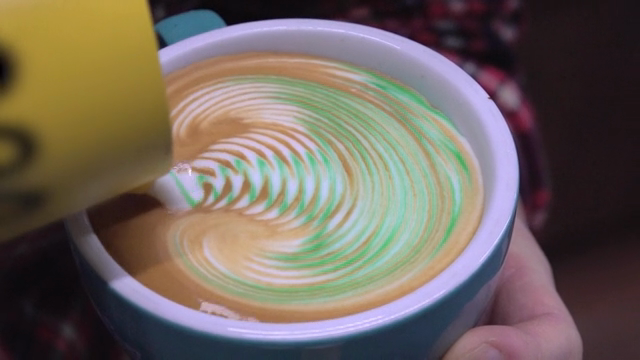 Colorful latte art being created on a coffee cup