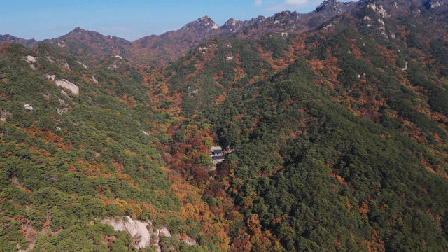 High peak with autumn foliage and a small temple