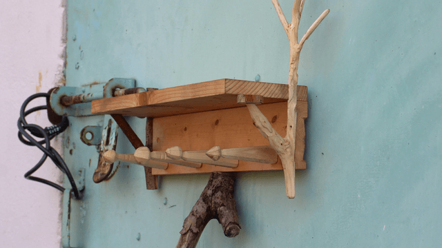 Wooden shelf supported by branches in front of an iron door