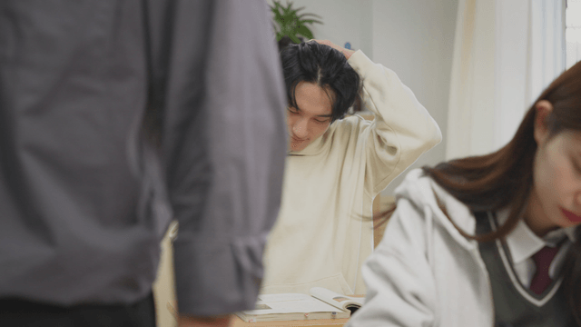 Teacher smiling while waking up a sleepy student in the classroom