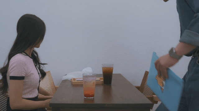 Man handing documents to a woman in a cafe