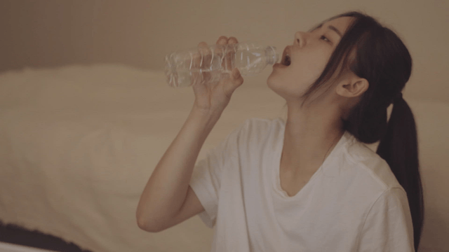 Young woman sitting in a cozy room and drinking water with pills