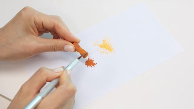 Hands scraping pastel on paper