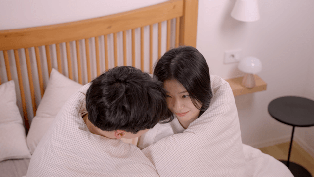 Happy couple wrapped in blankets on bed