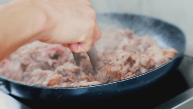 Meat being stir-fried on a hot pan