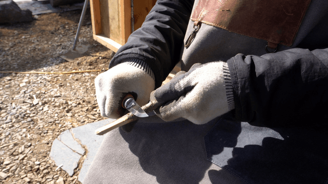 Woodcraft artisan carving a wooden stick with knife