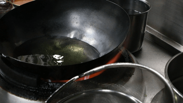 Oil heating in a wok on a stove