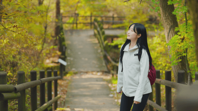 Long-haired young woman walking up autumn forest path