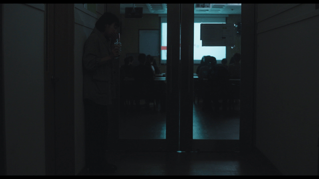 Woman spitting out blood from pack outside dark classroom