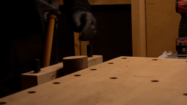 Craftsman securing a wooden piece on a workbench clamp