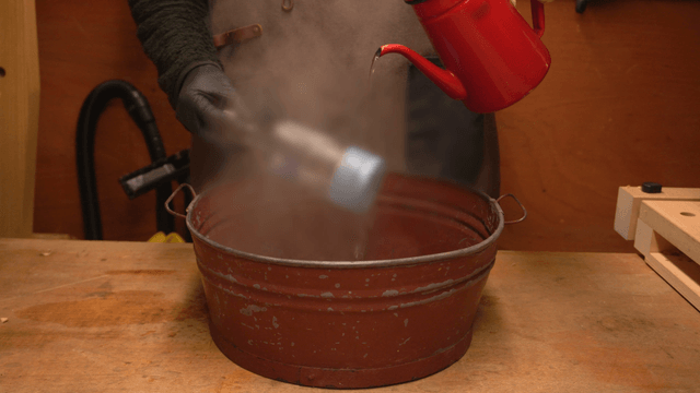 Craftsman pouring hot water into a bottle in workshop