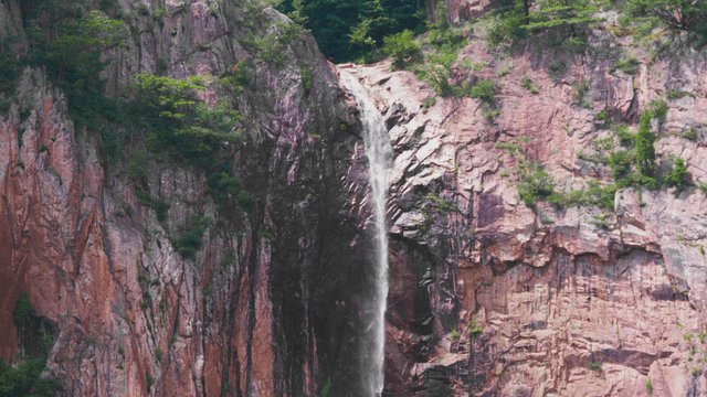 Small waterfall falling from high rock cliff