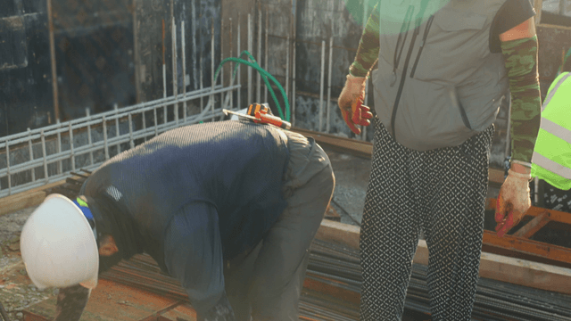 Construction workers handling steel rods