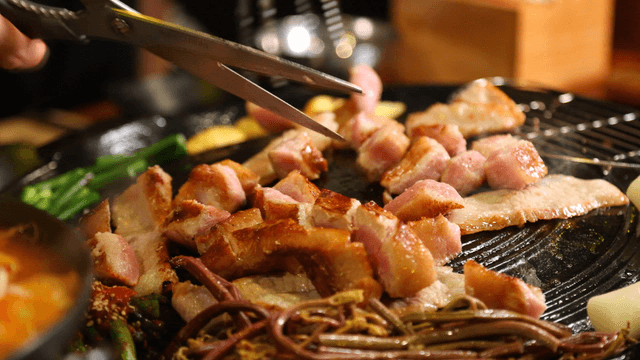 Pork jowl being cut on a hot pan