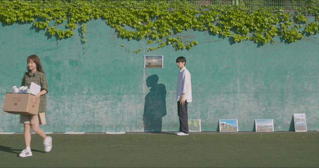 Woman leaving with box and man watching