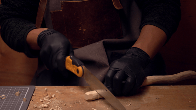 Person carving wood with a hand saw