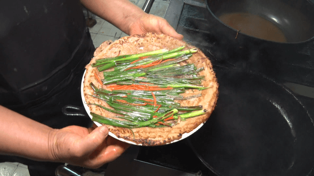 Green onion pancake being cooked in a kitchen