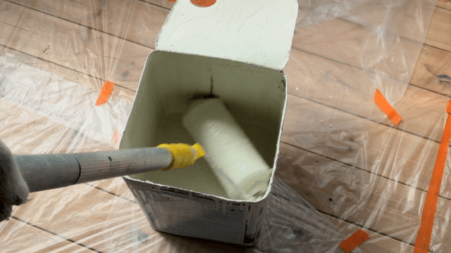 Paint roller dipped in white paint at construction site