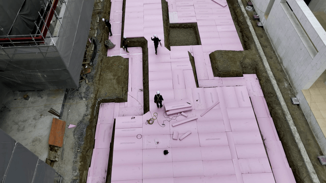 Workers laying insulation at a construction site