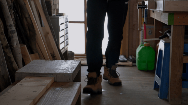 Person entering woodworking workshop with tools and thermos