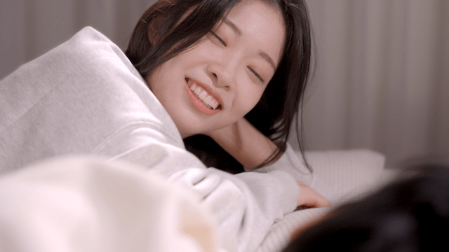 침대에 누워 따뜻하게 미소 지으며 남성을 바라보는 여성