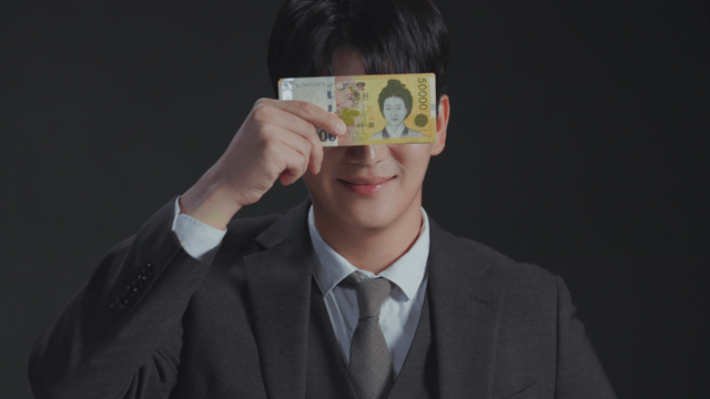 Man showing mixed expressions while covering his face with money