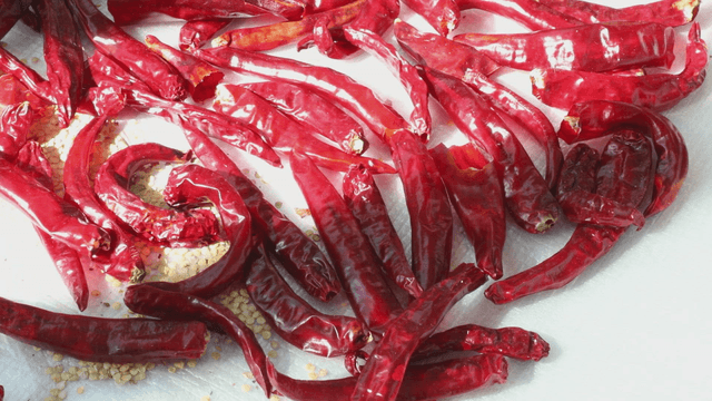 Dried red chili peppers on a white surface