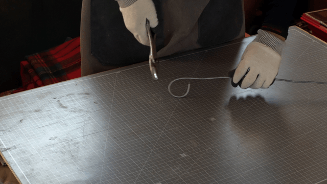 Hands bending wire with pliers on a table