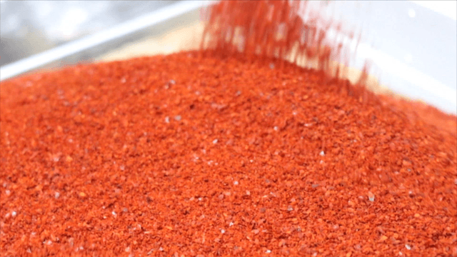 Coarse red chili powder being poured