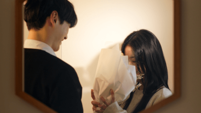 Couple happily exchanging flowers in front of mirror