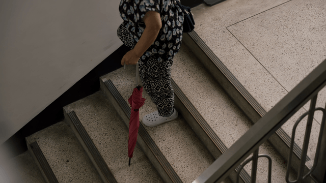 An elderly woman walking down the stairs
