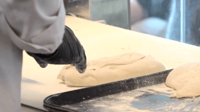 밀가루 위에서 반죽을 치대는 제빵사