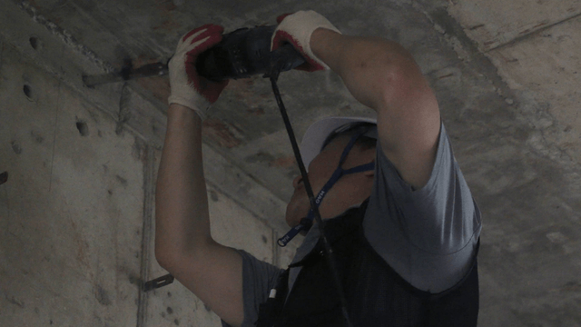 Worker drilling into a concrete ceiling
